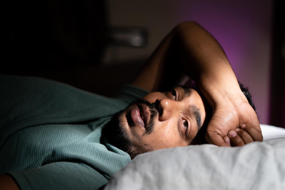 A man lays awake in bed suffering from insomnia