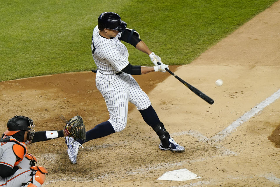 New York Yankees designated hitter Giancarlo Stanton, right, hits a grand slam during the fifth inning of a baseball game against the Baltimore Orioles, Monday, April 5, 2021, at Yankee Stadium in New York. Orioles catcher Pedro Severino, left, looks on. (AP Photo/Kathy Willens)