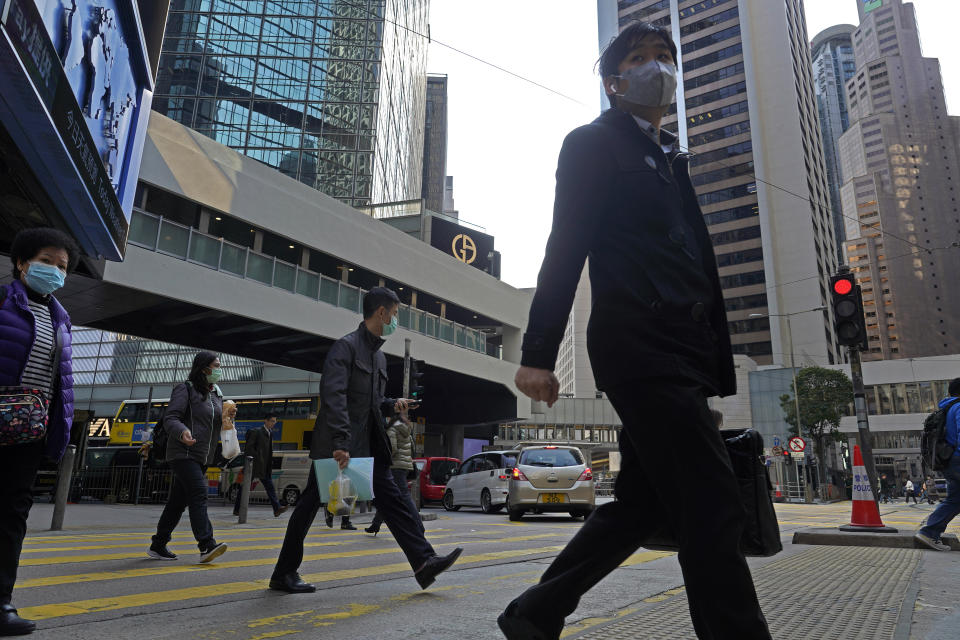 People wearing face mask walk at a downtown street in Hong Kong Monday, Feb. 17, 2020. COVID-19 viral illness has sickened tens of thousands of people in China since December. (AP Photo/Vincent Yu)