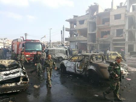 Syrian army soldiers inspect the site of a two bomb blasts in the government-controlled city of Homs, Syria, in this handout picture provided by SANA on February 21, 2016. REUTERS/SANA/Handout via Reuters