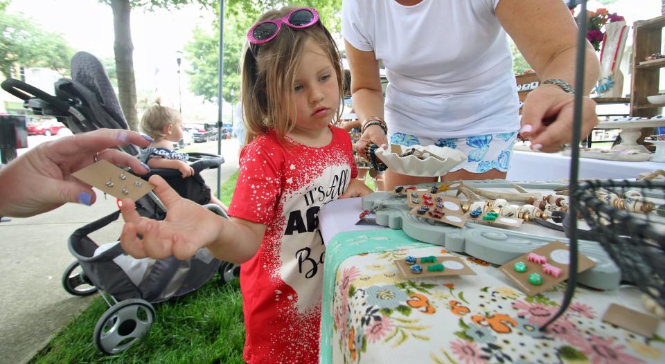 Five-year-old Evie Richard checks out the jewelry at the Katie Earl booth on the lawn of the Earl Scruggs Center in downtown Shelby Saturday morning, June 26, 2021, during the 18th annual Art of Sound Festival.