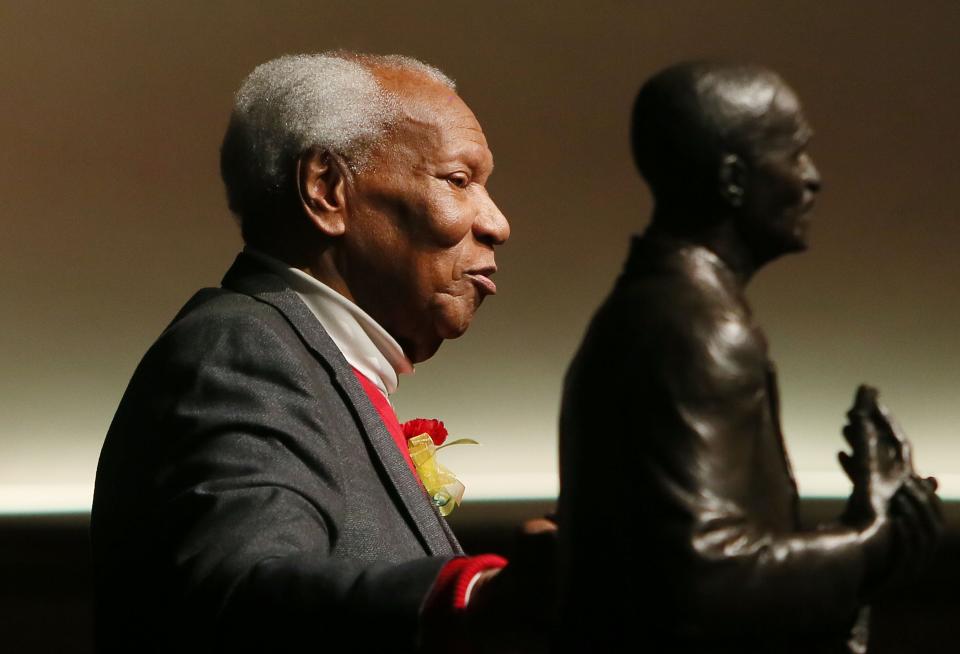 Simon Estes stands with a statue of George Washington Carver during the state's inaugural celebration of George Washington Carver Day.