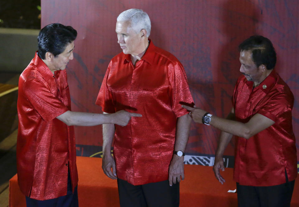 U.S. Vice President Mike Pence, center, watches Japanese Prime Minister Shinzo Abe, left, and Brunei Sultan Hassanal Bolkiah gesture before the start of the gala dinner family photo at the APEC summit in Port Moresby, Papua New Guinea, Saturday, Nov. 17, 2018. (AP Photo/Aaron Favila)
