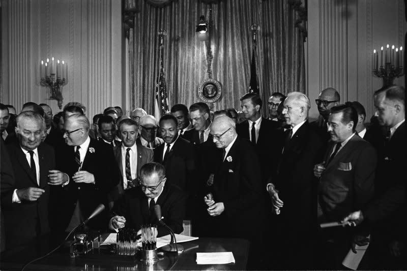 President Lyndon B. Johnson (C) signs the 1964 Civil Rights Act as the Rev. Martin Luther, standing behind him, and others watch on July 2, 1964, in the White House. File Photo by Cecil Stoughton/White House Press Office