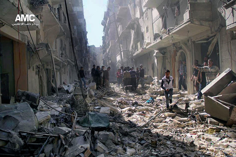 This Wednesday, March. 19, 2014 photo provided by the anti-government activist group Aleppo Media Center (AMC), which has been authenticated based on its contents and other AP reporting, Syrians inspect the rubble of destroyed buildings following a Syrian government airstrike in Aleppo, Syria. (AP Photo/Aleppo Media Center AMC)