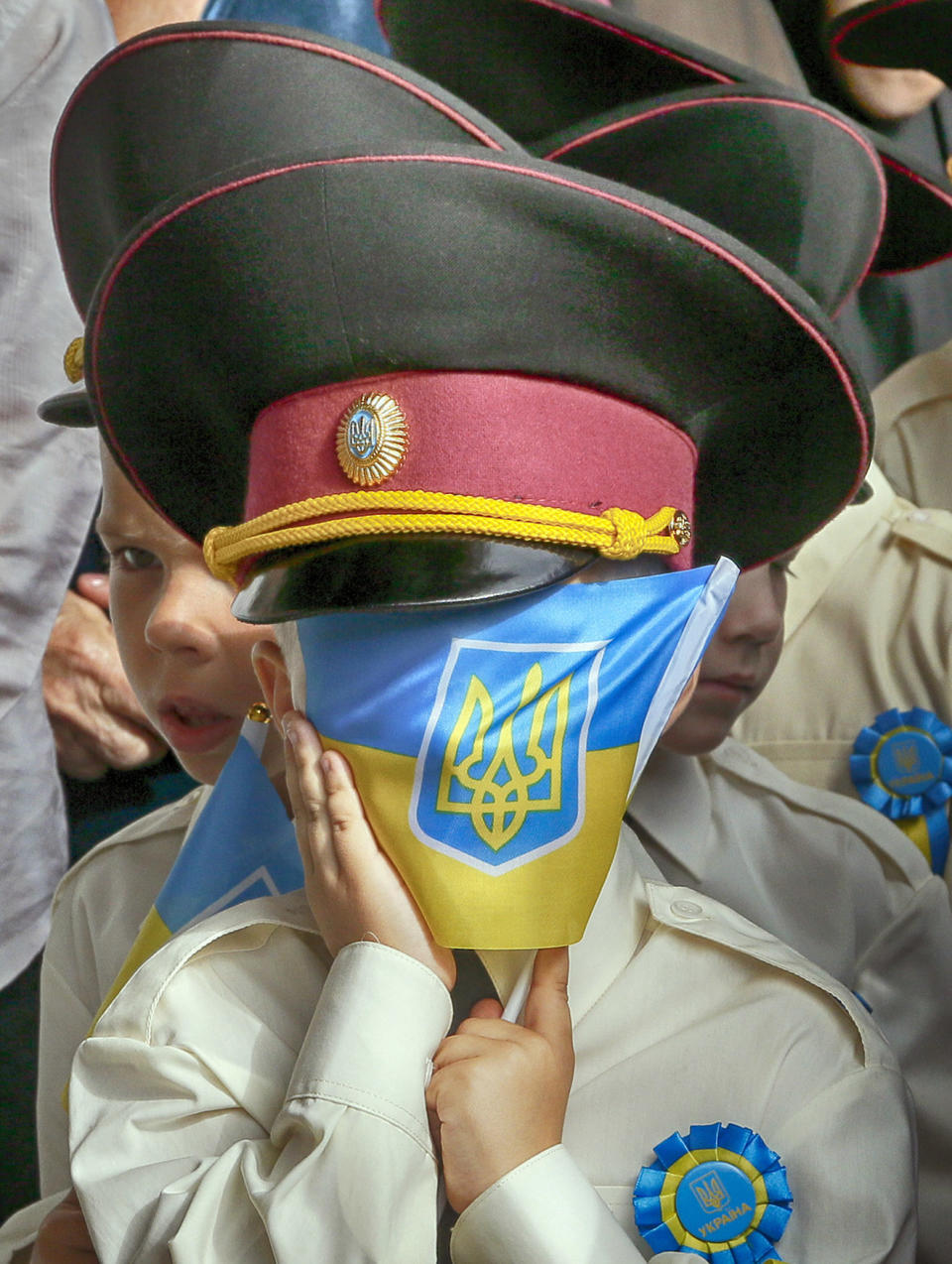 A cadet covers his face with a national flag as he attends a ceremony on the occasion of the first day