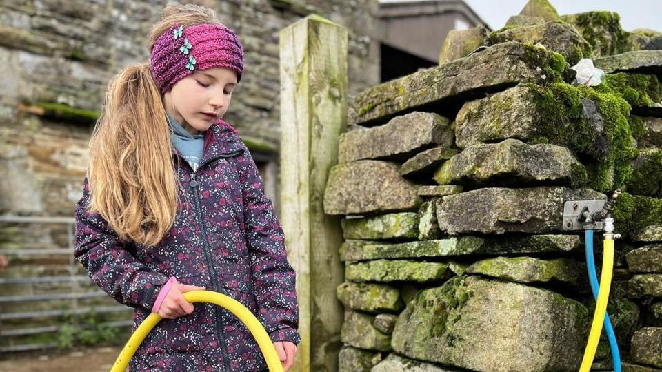 Amanda Owen's daughter fills up bucket in photo from Ravenseat Farm