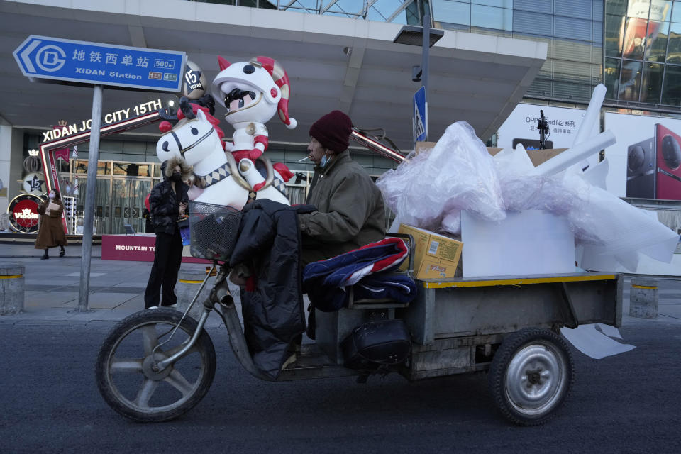 A man transports materials past by a mall in Beijing, Thursday, Dec. 29, 2022. China is on a bumpy road back to normal life as schools, shopping malls and restaurants fill up again following the abrupt end of some of the world's most severe restrictions even as hospitals are swamped with feverish, wheezing COVID-19 patients. (AP Photo/Ng Han Guan)
