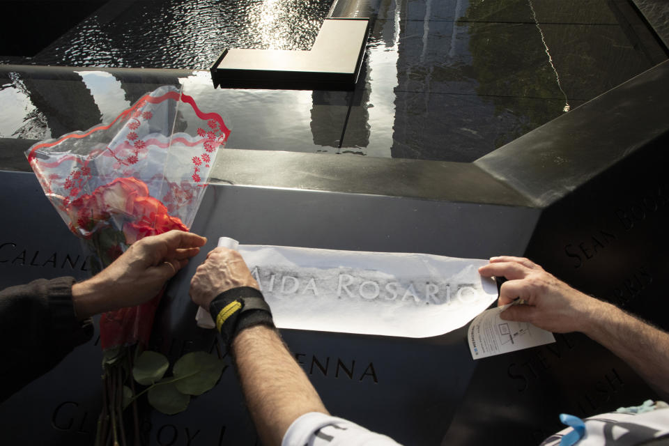 Louis Gonzalez makes a rubbing of his sister's name at the National September 11 Memorial, Wednesday, Sept. 11, 2019 in New York. Aida Rosario was killed during the attacks of Sept. 11, 2001. (AP Photo/Mark Lennihan)