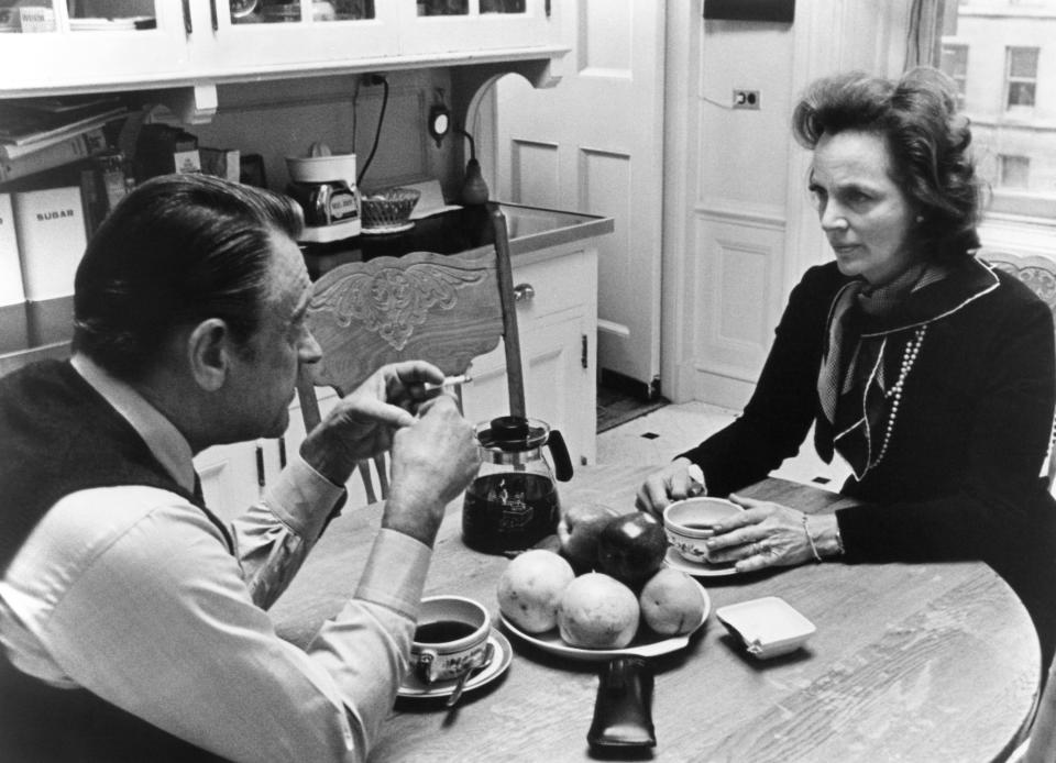 A man and a woman sitting at a table in a kitchen looking at each other