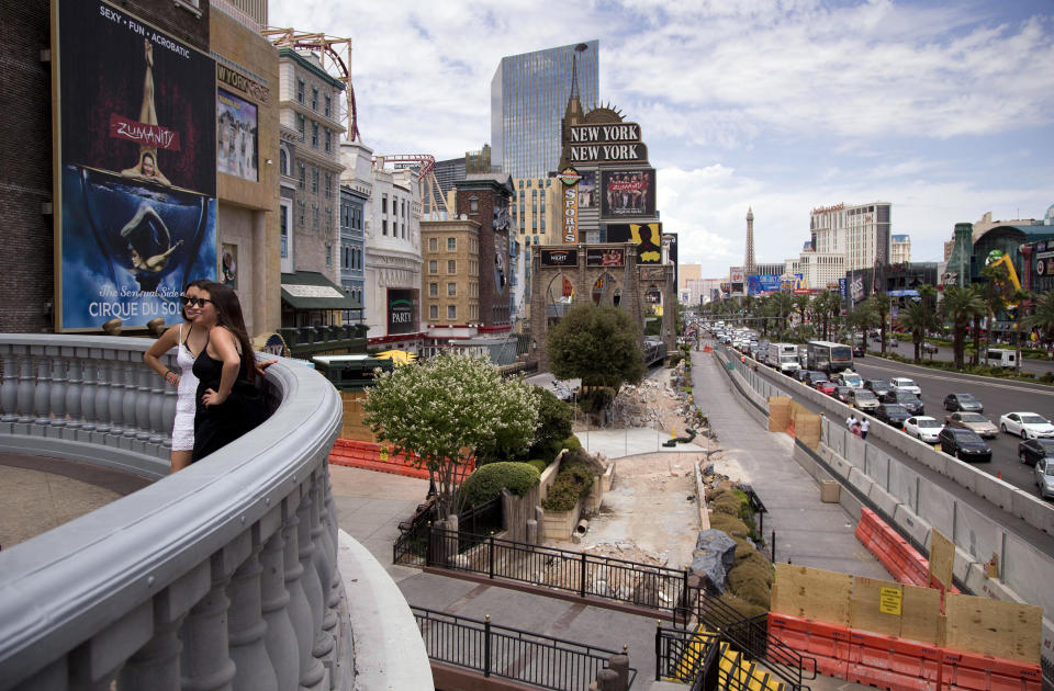 Tourists pose for a photo on a balcony overlooking Las Vegas Boulevard outside the New York-New York casino, Friday, July 26, 2013, in Las Vegas. MGM Resorts International says it will relocate a Sept. 11 memorial which sat in front of the casino to make way for a $100 million renovation of the promenade in front of 16 year-old Manhattan-themed casino and the adjoining Monte Carlo. (AP Photo/Julie Jacobson)