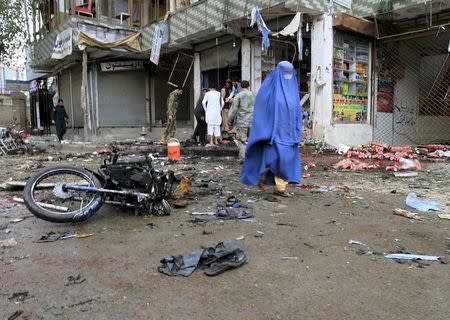 An Afghan woman walks at the site of a suicide attack in Jalalabad April 18, 2015. REUTERS/Parwiz