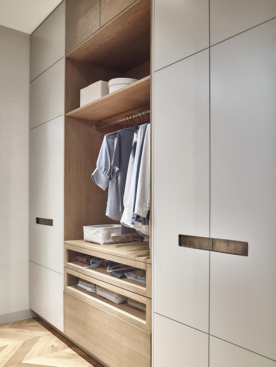 closet with part enclosed and part shelving with some hanging, open shelving and drawers, herringbone floor