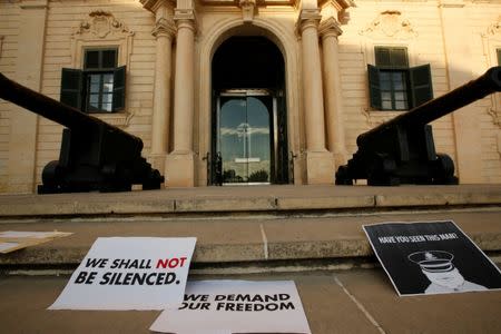 Posters left by masked students holding a silent protest following the assassination of the investigative journalist Daphne Caruana Galizia in a car bomb attack three days ago, are seen on the steps of the office of the Prime Minister at Auberge de Castille in Valletta, Malta, October 19, 2017. REUTERS/Darrin Zammit Lupi