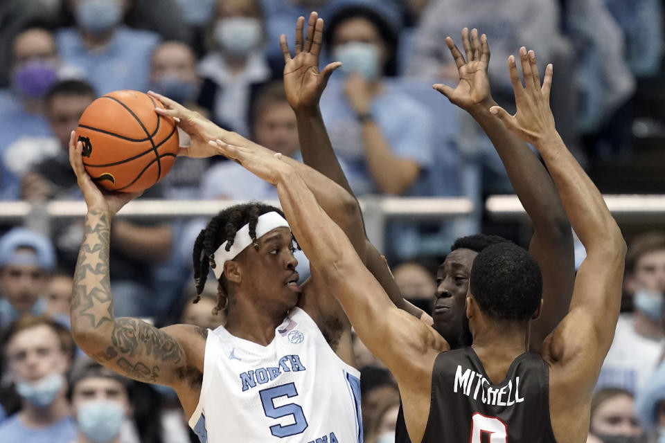 North Carolina forward Armando Bacot (5) looks to pass while Brown forward Nana Owusu-Anane, rear, and guard David Mitchell (0) defend during the second half of an NCAA college basketball game in Chapel Hill, N.C., Friday, Nov. 12, 2021. (AP Photo/Gerry Broome)