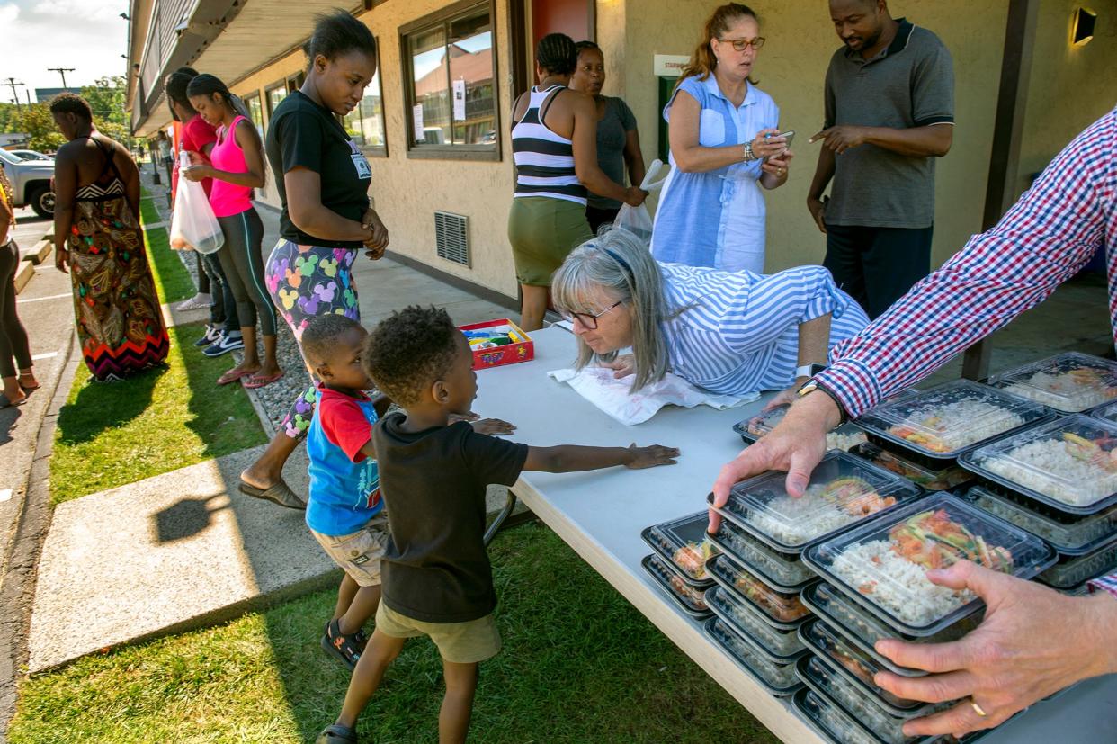 Ellen Koswick, center, of Framingham, helps serve lunch to Haitian asylum seekers last August at the Red Roof Inn in Framingham. Koswick, is a local Realtor who is a member of the MetroWest Chamber of Commerce. Legislators are working on a bill that would standardize the amount of time that homeless people can stay in hotels being used as emergency shelters.