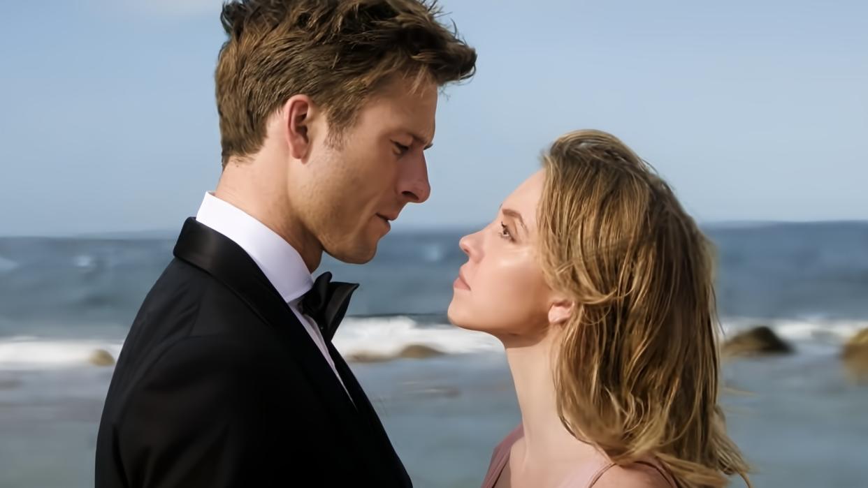  (left to right) Glen Powell looks at Sydney Sweeney in front of the ocean in Anyone But You. 