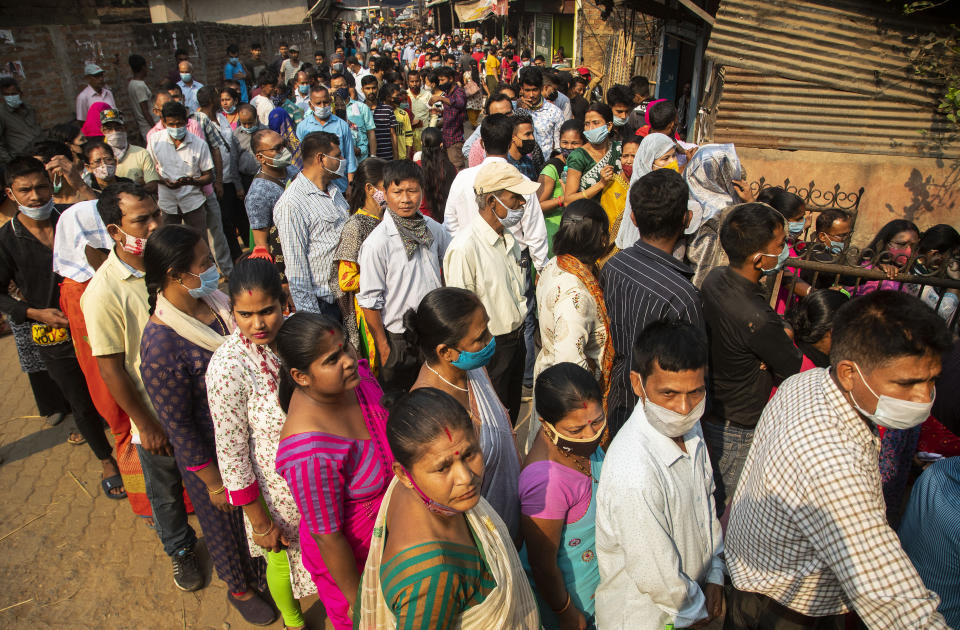 People stand in queue to cast their votes in a polling station during the third phase of assembly election in Gauhati, India, Tuesday, April 6, 2021. (AP Photo/Anupam Nath)