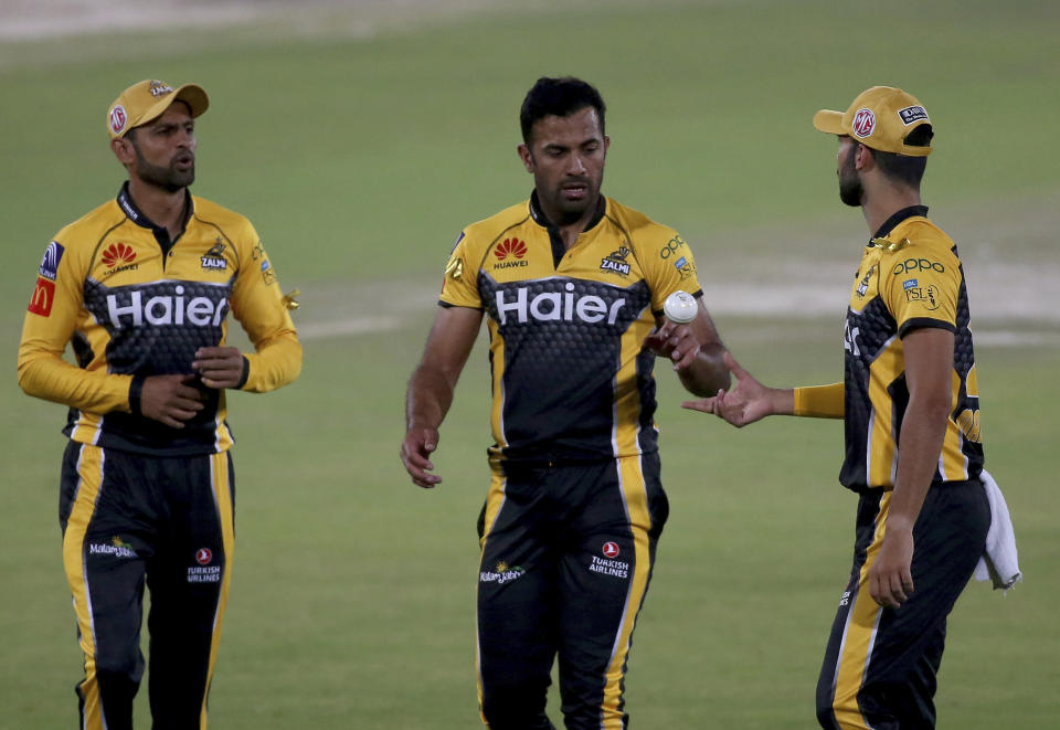 Peshawar Zalmi' Wahab Riaz, center, talks to teammates Shoaib Malik, left, and Saqib Mahmood while he walks toward his bowling point during a Pakistan Super League T20 cricket match between Islamabad United and Peshawar Zalmi at the National Stadium, in Karachi, Pakistan, Saturday, Feb. 27, 2021. (AP Photo/Fareed Khan)