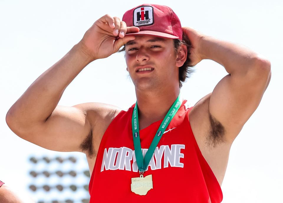 Norwayne junior Dillon Morlock proudly puts back on his International Harvester hat after winning the discus and being crowned with the gold medal to remember his grandfather, Jim, who passed away this past April.