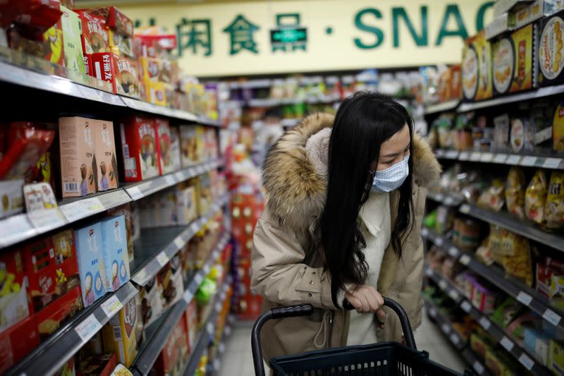 A woman wearing a face mask looks for products at a supermarket, as the country is hit by an outbreak of the new coronavirus, in Beijing