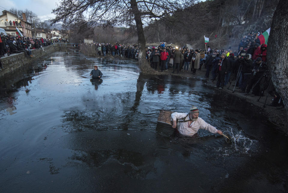 A drummer breaks ice prior to the Epiphany ritual, in Kalofer, Bulgaria, Monday, Jan. 6, 2020. Thousands of Orthodox Christian worshippers plunged into the icy waters of rivers and lakes across Bulgaria on Monday to retrieve crucifixes tossed by priests in ceremonies commemorating the baptism of Jesus Christ. In the mountain city of Kalofer, in central Bulgaria, dozens of men dressed in white embroidered shirts waded into the frigid Tundzha River waving national flags and singing folk songs. (AP Photo)