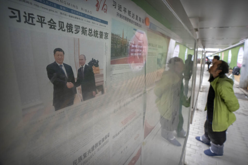 FILE - People look at newspapers near a copy of the Guangming Daily newspaper with a headline about Chinese President Xi Jinping's visit to Russia at a stand in Beijing, Tuesday, March 21, 2023. China's muted reaction to the Wagner mercenary group uprising against Russia's military belies Beijing's growing anxieties over the war in Ukraine and how this affects the global balance of power. (AP Photo/Mark Schiefelbein, File)