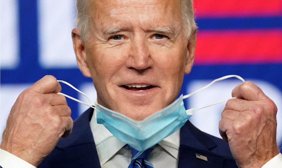 Biden smiles as he pulls off his face mask before speaking in Wilmington, Del., Nov. 4. (Kevin Lamarque/Reuters)