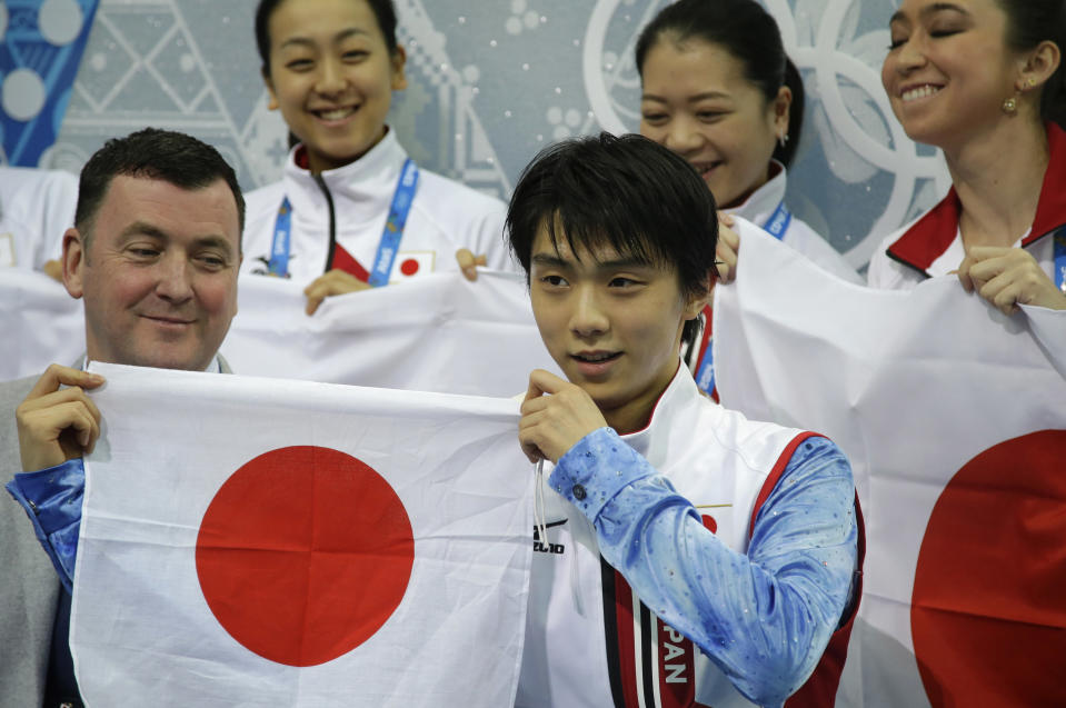 Yuzuru Hanyu of Japan holds up the national flag after competing in the men's team short program figure skating competition at the Iceberg Skating Palace during the 2014 Winter Olympics, Thursday, Feb. 6, 2014, in Sochi, Russia. (AP Photo/Darron Cummings, Pool)