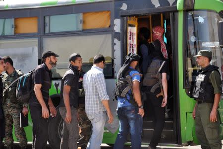 Rebel fighters board a bus to evacuate the besieged Waer district in the central Syrian city of Homs, under an agreement between rebels and Syria's army, in this handout picture provided by SANA on September 26, 2016. SANA/Handout via REUTERS