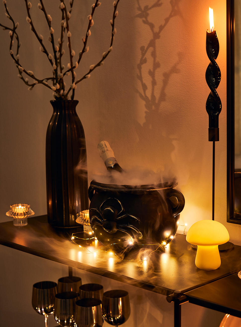 the witch's cauldron with dry ice and a bottle of alcohol in it on a table with fairy lights and other spooky decor