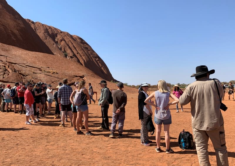 People line up to climb Uluru, formerly known as Ayers Rock, the day before a permanent ban on climbing the monolith takes effect following a decades-long fight by indigenous people to close the trek, near Yulara