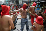 A hooded Filipino penitent has two pointed wooden sticks tied to his arms as he joins others in Maundy Thursday rituals to atone for sins on April 17, 2014 in suburban Mandaluyong, east of Manila, Philippines. The bizarre ritual is frowned upon by church leaders in this predominantly Roman Catholic country. (AP Photo/Aaron Favila)