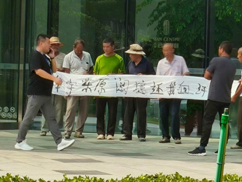 西安中心樓樓下的農民工拉著「華宇東原閱境還我血汗錢」的橫幅。    圖：翻攝自@whyyoutouzhele