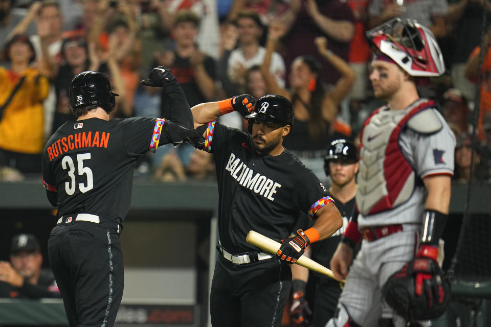 Baltimore Orioles' Adley Rutschman (35) is greeted near the dugout by Anthony Santander after hitting a solo home run as Minnesota Twins catcher Ryan Jeffers looks on during the sixth inning of a baseball game, Friday, June 30, 2023, in Baltimore. (AP Photo/Julio Cortez)
