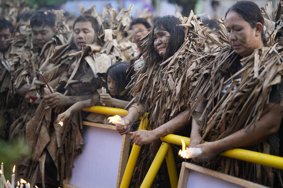 Devout Catholics, dressed in dried banana leaves, stand for mass at the church of Saint John the Baptist during the mud festival at Bibiclat, Nueva Ecija province, northern Philippines, Monday, June 24, 2024. (AP Photo/Aaron Favila)