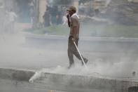 A protester supporting the opposition Cambodia National Rescue Party (CNRP) covers his nose as police fire tear gas during clashes near the Royal Palace in central Phnom Penh September 15, 2013. (REUTERS/Samrang Pring)