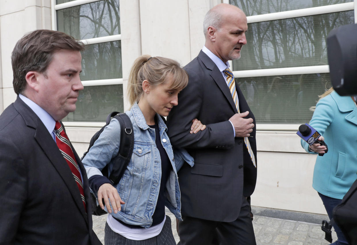 Allison Mack, center, leaves federal court Tuesday, April 24, 2018, in the Brooklyn borough of New York. Federal prosecutors say the television actress best known for playing a young Superman's close friend has been charged with sex trafficking for helping recruit women to be slaves of a man who sold himself as a self-improvement guru. (AP Photo/Kathy Willens)