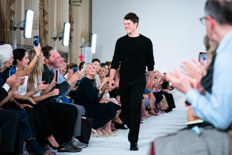 Fashion designer Wes Gordon walks out to applause after his Carolina Herrera Fall 2022 collection was modeled during Fashion Week, Monday, Sept. 12, 2022, in New York. Martha Stewart, middle left, looks on. (AP Photo/Julia Nikhinson)