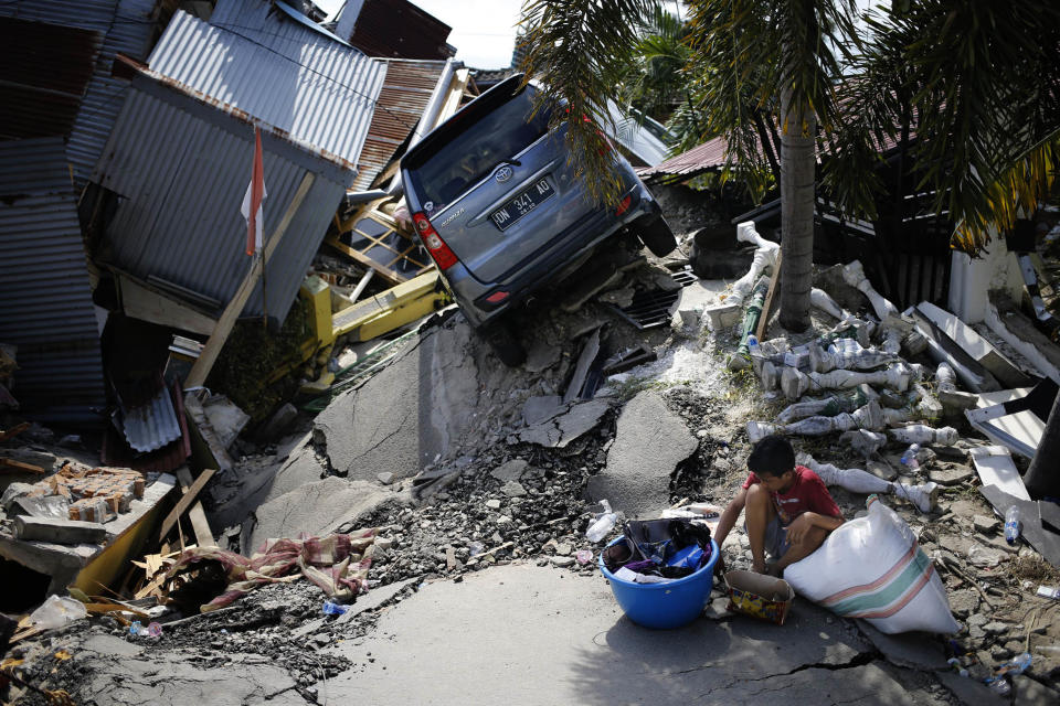 A boy sits with items salvaged from the ruins of a family member's house in the Balaroa neighborhood in Palu, Central Sulawesi, Indonesia Indonesia, Tuesday, Oct. 2, 2018. Desperation was visible everywhere Tuesday among victims receiving little aid in areas heavily damaged by a massive earthquake and tsunami, four days after the disaster devastated parts of Indonesia's central Sulawesi island. (AP Photo/Dita Alangkara)