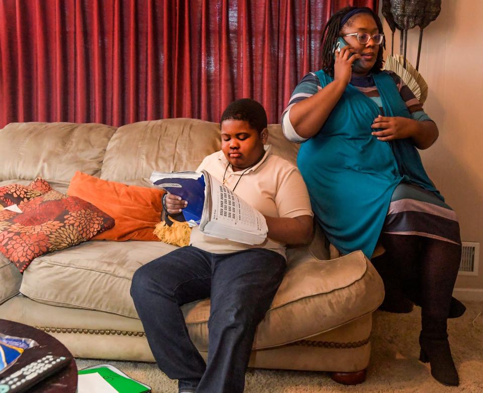 Desiree Carmichael talks on the phone with son Zion Carmichael while helping her other son, Xavier Gelpin, with his homework at her home in Pleasant Grove, Ala., on Nov. 2, 2023.