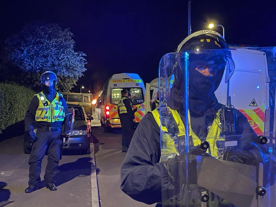 Police officers on Howell Road in Cardiff as they faced a ‘large scale disorder’ at the scene of a serious road traffic collision (PA)