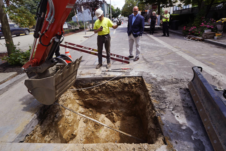 Richie Nero, left, of Boyle & Fogarty Construction, guides a backhoe operator while pulling the old lead residential water supply line from a home where service was getting upgraded to copper, Thursday, June 29, 2023, in Providence, R.I. At center watching the process is Providence Water general manager Ricky Caruolo. Health and environmental groups have been fighting for lead-free water to drink in Providence for at least a decade. (AP Photo/Charles Krupa)