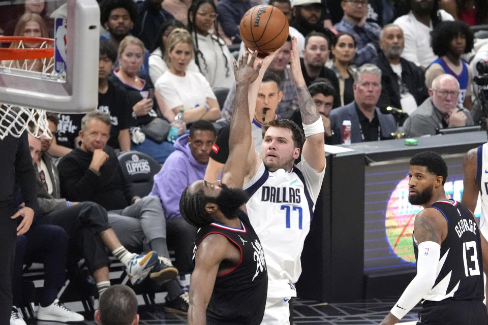 Dallas Mavericks guard Luka Doncic, center, shoots as Los Angeles Clippers guard James Harden, left, defends and forward Paul George watches during the second half in Game 2 of an NBA basketball first-round playoff series Tuesday, April 23, 2024, in Los Angeles. (AP Photo/Mark J. Terrill)