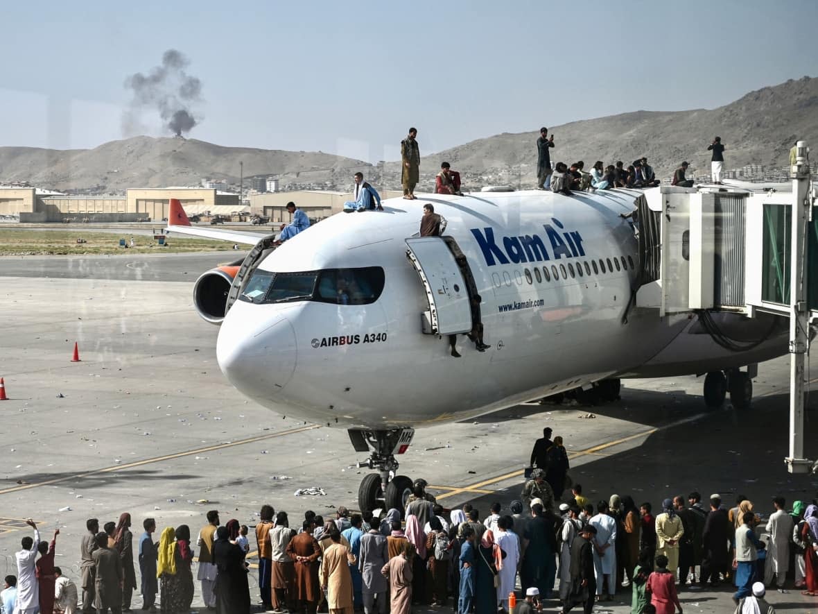 People attempting to flee the Taliban climb on a plane at the Kabul airport on August 16, 2021. (Wakil Kohsar/AFP/Getty Images - image credit)