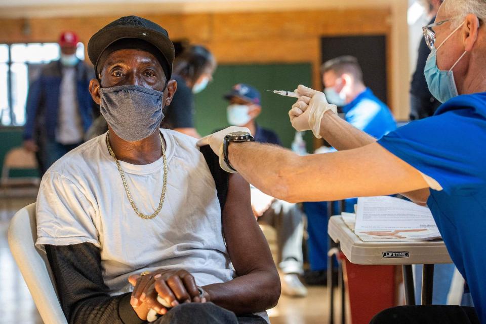 man staring at the camera, about to get COVID-19 shot administered by nurse