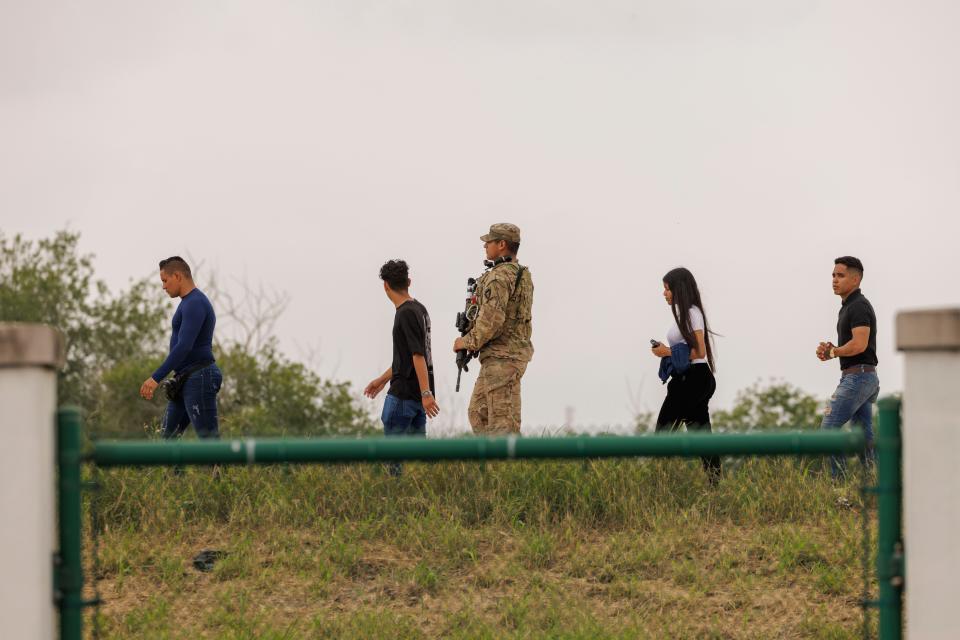 A Texas National Guard member escorts migrants to Border Patrol agents on May 4, 2023 in Brownsville, Texas.