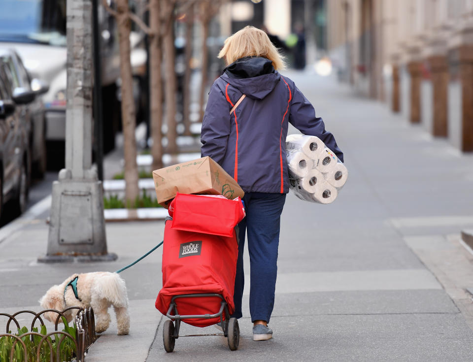 A woman carries groceries and toilet paper on March 18, 2020  New York City. - The coronavirus outbreak has transformed the US virtually overnight from a place of boundless consumerism to one suddenly constrained by nesting and social distancing.The crisis tests all retailers, leading to temporary store closures at companies like Apple and Nike, manic buying of food staples at supermarkets and big-box stores like Walmart even as many stores remain open for business -- albeit in a weirdly anemic consumer environment. (Photo by Angela Weiss / AFP) (Photo by ANGELA WEISS/AFP via Getty Images)