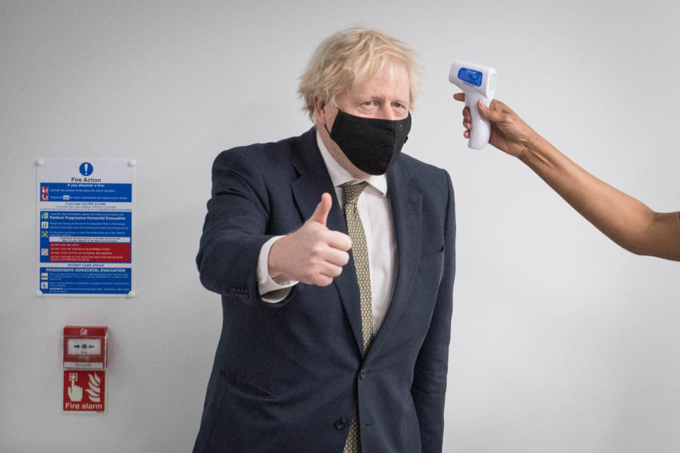 Prime Minister Boris Johnson gives a thumbs up as he has his temperature taken during a visit to view the vaccination programme at Chase Farm Hospital in north London, part of the Royal Free London NHS Foundation Trust. The NHS is ramping up its vaccination programme with 530,000 doses of the newly approved Oxford/AstraZeneca Covid-19 vaccine jab available for rollout across the UK.