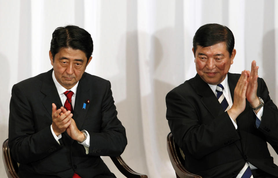 FILE - In this Sept. 14, 2012 file photo, Japan's opposition Liberal Democratic Party presidential candidates, former Prime Minister Shinzou Abe, left, and former Defense Minister Shigeru Ishiba, applaud during an official announcement for the race in Tokyo. Four lawmakers vying for leadership of Japan's main opposition party have promised to protect Japan's control of islands at the center of a territorial furor with China. (AP Photo/Junji Kurokawa, File)